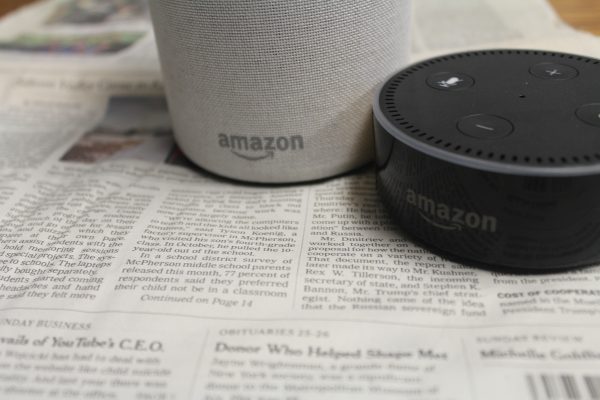Amazon echo and the echo dot sitting atop of newspapers.