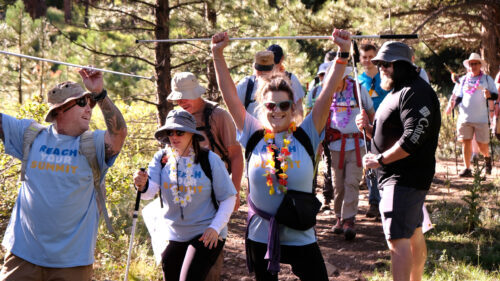 Group of hikers cheering and lifting white canes in the air.