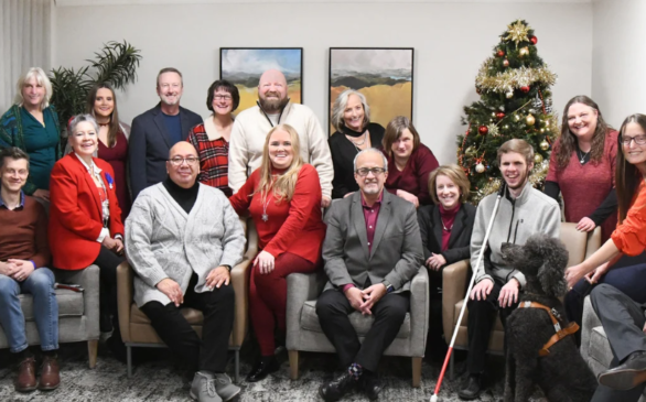 AINC staff and board posing in front of Christmas tree
