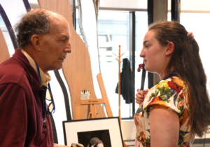 Robert conversing with a young woman in front of artwork