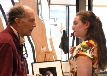 Robert conversing with a young woman in front of artwork